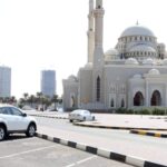 Sharjah UAE National Day 2024 free parking announcement with cityscape in the background.